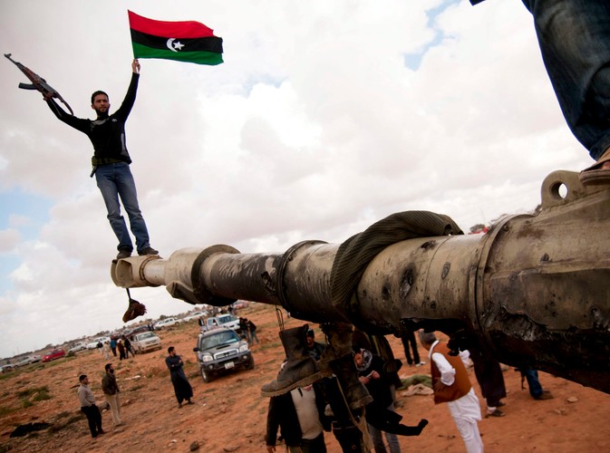 Rebelianci na spalonym czołgu, należącym do sił Muammara Kadafiego, zniszczonym podczas francuskiego nalotu 25 km od Bengazi
