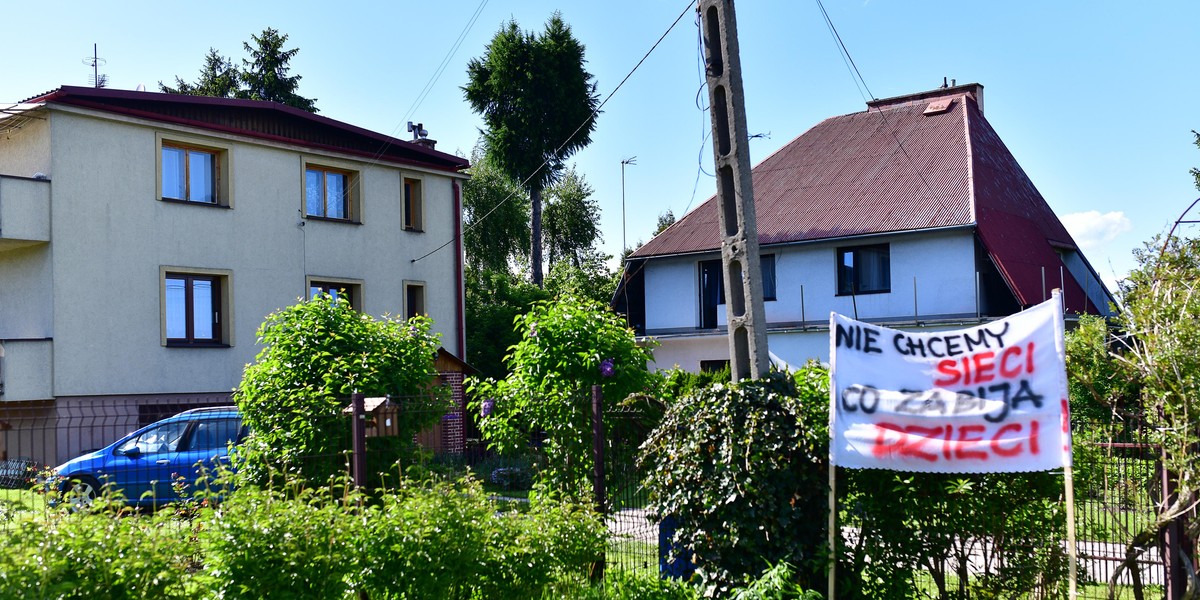 Maszt stanie pośrodku domów jednorodzinnych.