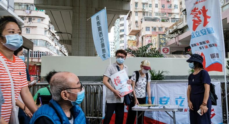 People stand at a booth where passersby can give their signatures in support of a new security law in Hong Kong