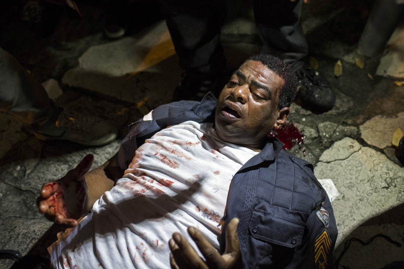 Ranny policjant leży na ziemi po starciach z demonstrantami w Rio de Janeiro