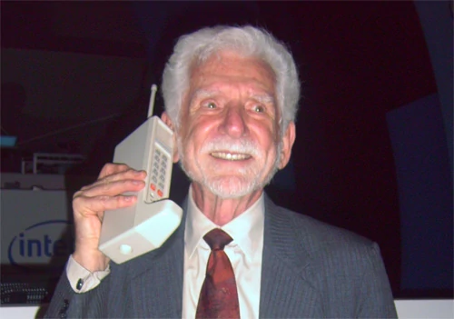 Dr. Martin Cooper - pierwszy człowiek, który kiedykolwiek rozmawiał przez telefon komórkowy. Na zdjęciu, z pierwszą komórkową cegłą... Wikimedia Commons.