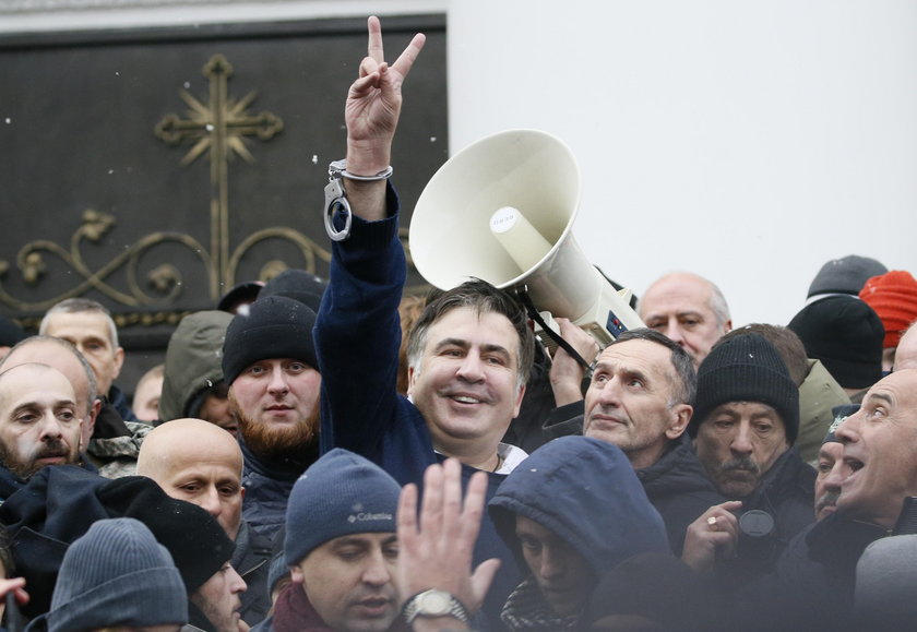Supporters of Georgian former President Mikheil Saakashvili break a window a police car carrying Saa