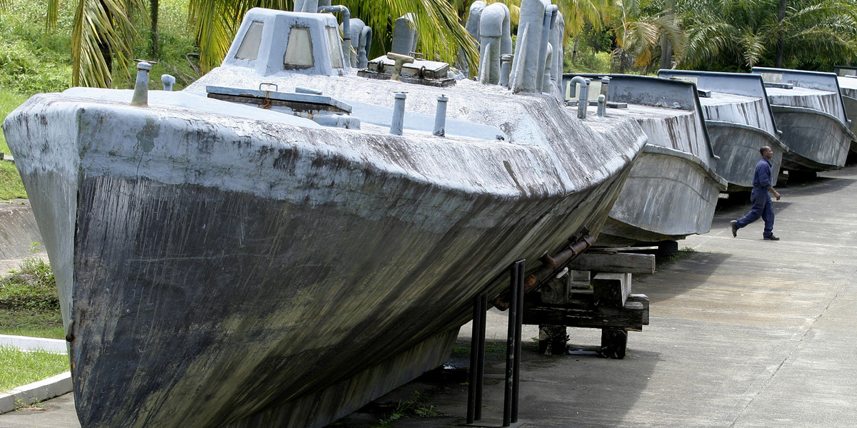 A man walks between a makeshift fiberglass submarine (front) and speedboats, used to smuggle cocaine used by Colombian drug traffickers, in Buenaventura June 24, 2008. Colombians who thought they had seen everything in the war on drugs were treated to something new this year: cocaine smuggling in a submarine.