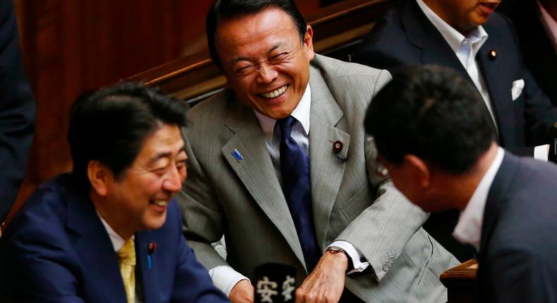 Financial Minister Taro Aso, center, and Japanese Prime Minister Shinzo Abe, left, share a light moment during a plenary session at the lower house in Tokyo, Thursday, July 16, 2015.