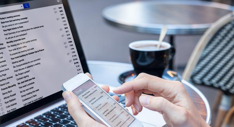 Emailing on laptop and mobile device at coffee shop