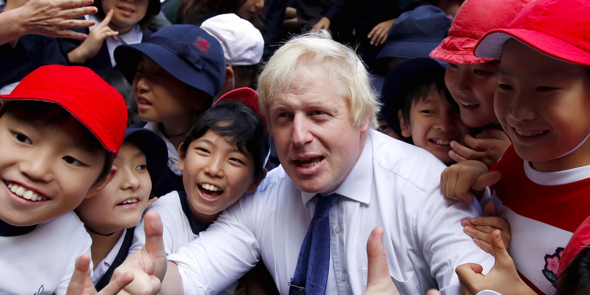 London's Mayor Boris Johnson poses for a photo with school children after a game of Street Rugby with a group of Tokyo children, outside the Tokyo Square Gardens building October 15, 2015.