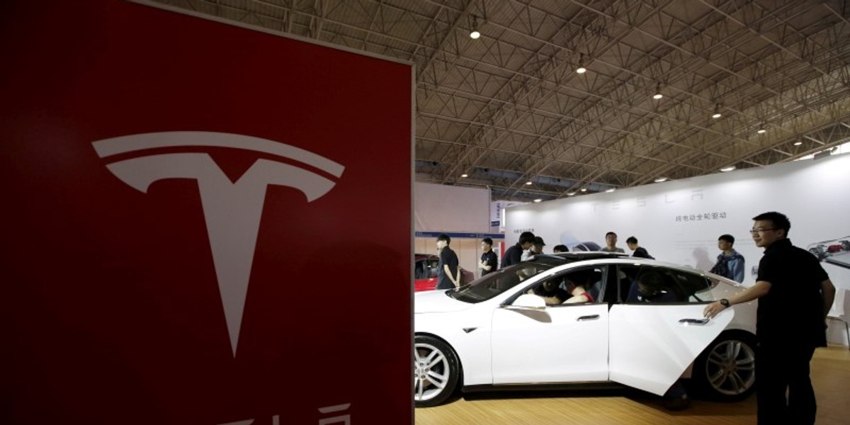 People visit a Tesla Model S car during the Auto China 2016 in Beijing