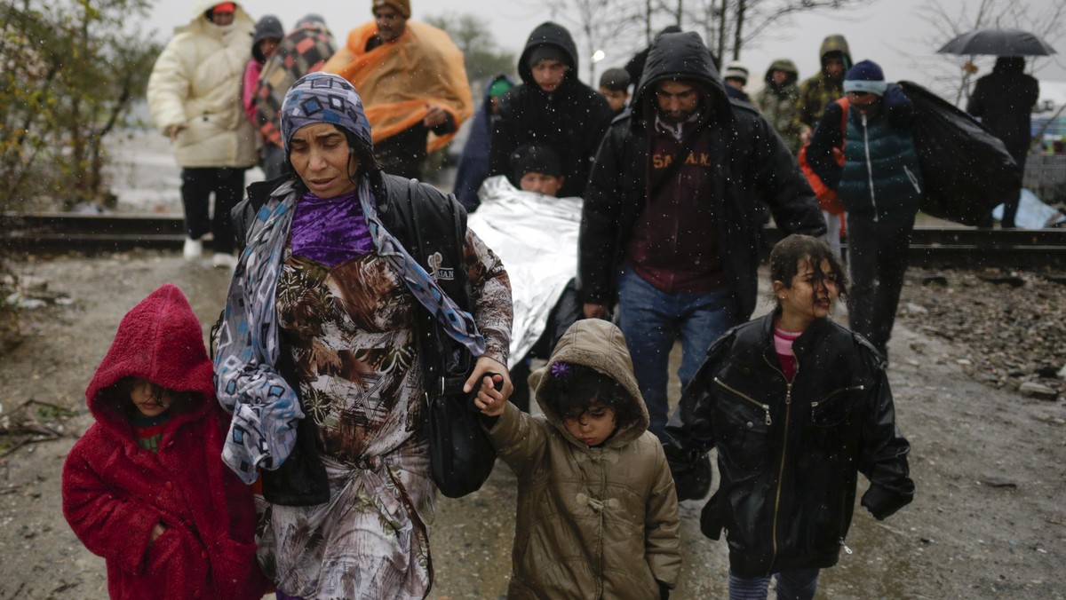 Migrants walk under rain after crossing the border from Greece into Macedonia, near Gevgelija