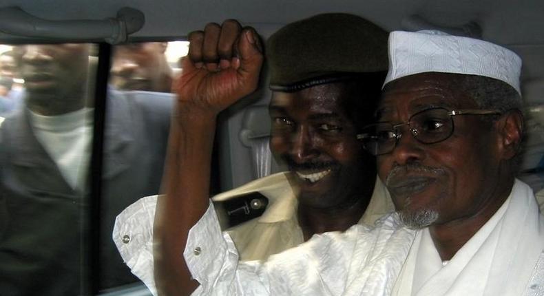 Former Chad President Hissene Habre (R) raises his fist in the air as he leaves a court in Dakar escorted by a Senegalese policeman November 25, 2005.   REUTERS/Aliou Mbaye