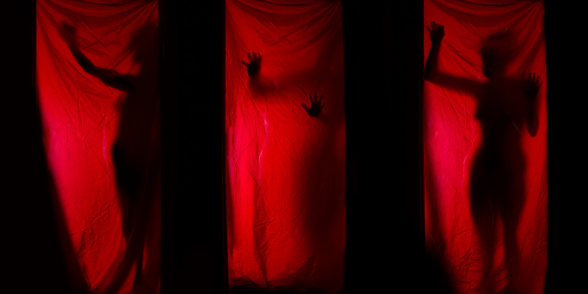 Woman behind red curtains