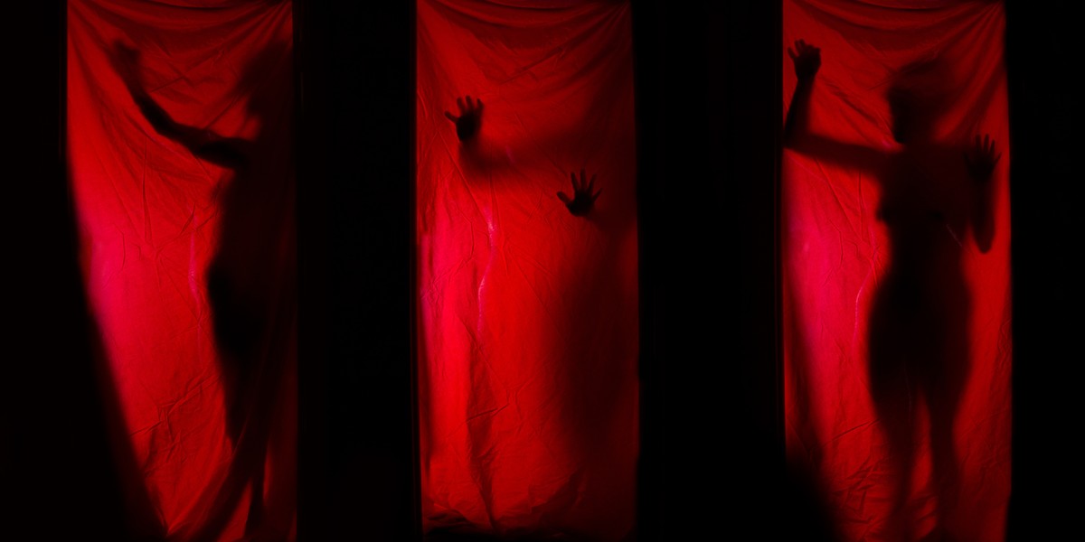 Woman behind red curtains