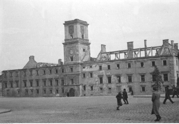 Warszawa. Przechodnie na placu Zamkowym i zniszczony Zamek Królewski (1940 r.)