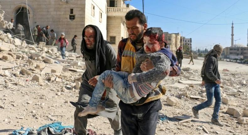 A Syrian civil defence volunteer, known as the White Helmets, carries a boy rescued from the rubble following a reported barrel bomb attack on the Bab al-Nairab neighbourhood of the northern Syrian city of Aleppo on November 24, 2016