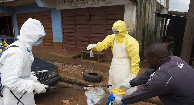 Health workers in protective equipment handle a sample taken from the body of someone who is suspected to have died from Ebola virus, near Rokupa Hospital, Freetown October 6, 2014.  REUTERS/Christopher Black/WHO/Handout via Reuters