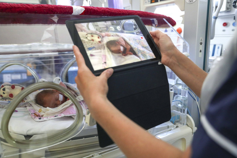 W okresie pandemii ograniczono możliwość odwiedzin w szpitalach. Pielęgniarka nagrywa niemowlę, by przesłać film rodzinie