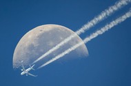 A commercial airplane flies past the moon above Geneva