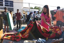 A woman stands near an injured person outside of a hospital after an earthquake hit Sembalun Selong village in Lombok Timur