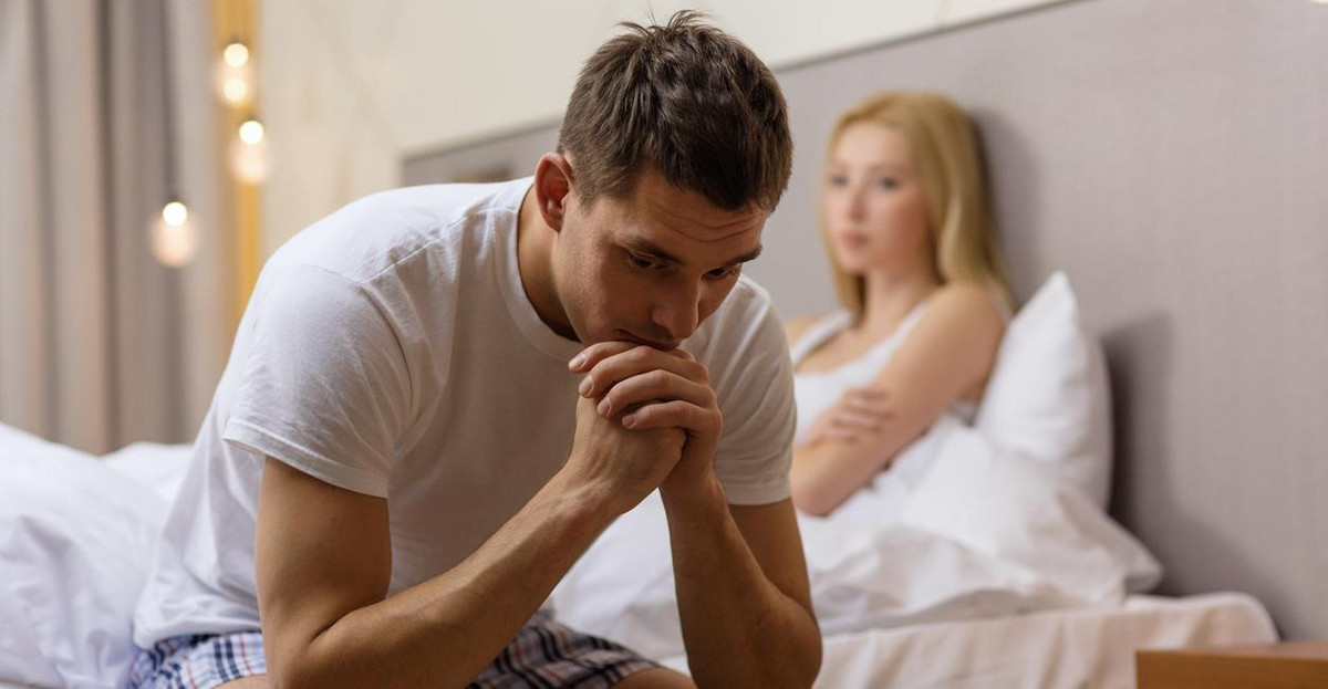 upset man sitting on bed with disappointed woman