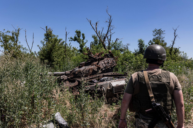 Ukraiński żołnierz przed zniszczonym rosyjskim czołgiem