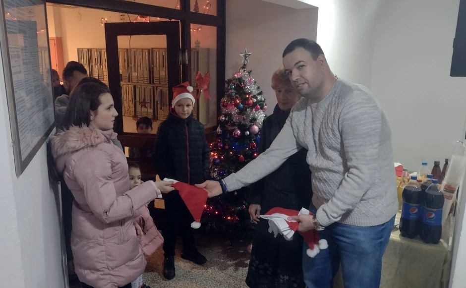 Upravnik zgrade Miloš Stefanović deli novogodišnje kape deci i komšijama iz zgrade u Ulici generala Milojka Lešjanina 65 
