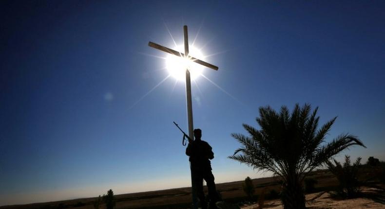 A member of the Iraqi Christian forces Kataeb Babylon (Babylon Brigades) stands guard beneath a cross at the Mar Behnam Syriac Catholic monastery in Khidr Ilyas