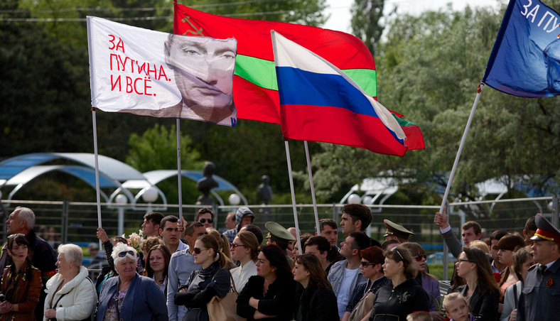 Ludzie niosą rosyjską flagę z portretem prezydenta Władimira Putina z napisem "Jesteśmy za Putinem!" w Tyraspolu, Naddniestrze, 9 maja 2014 r.
