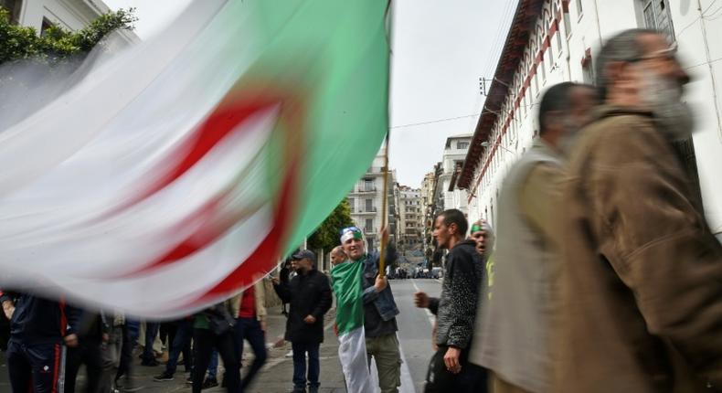 An Algerian protester waves the national flag during a weekly anti-government demonstration in the capital Algiers on March 13 before the rallies were suspended because of the novel coronavirus