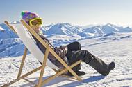 Girl sunbathing in a deckchair, snowy mountain landscape