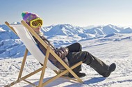 Girl sunbathing in a deckchair, snowy mountain landscape