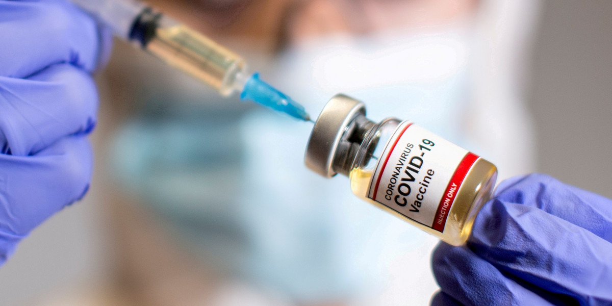 FILE PHOTO: A woman holds a medical syringe and a small bottle labeled "Coronavirus COVID-19 Vaccine