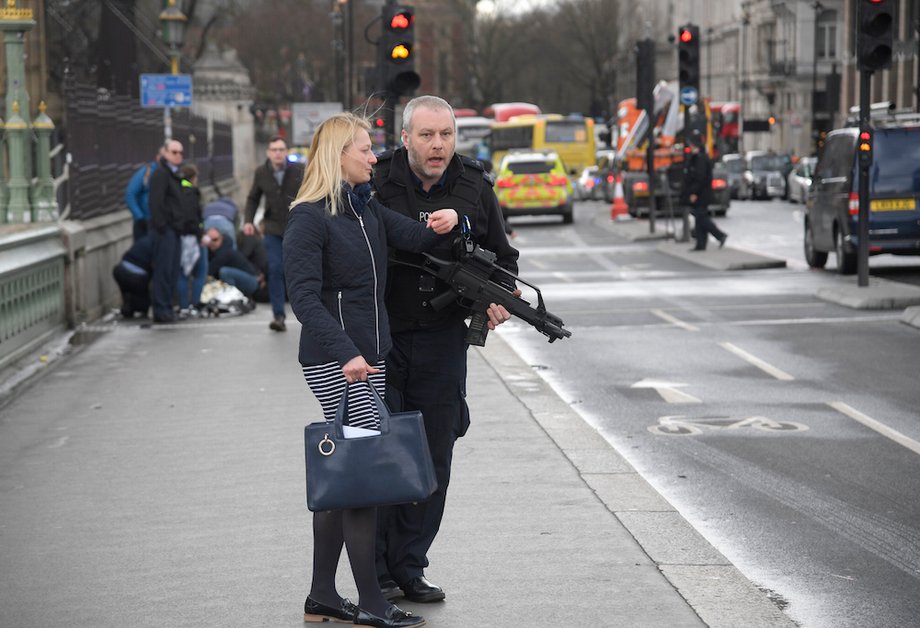 An armed police officer assists a woman after an incident on Westminster Bridge in London, March 22, 2017.