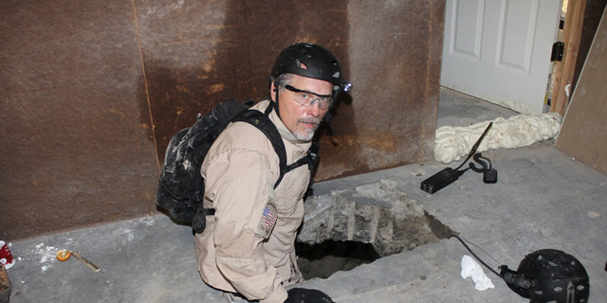An agent from the San Diego Tunnel Task Force lowers himself into the passageway of a tunnel found under the US-Mexico border in San Diego, November 26, 2010.