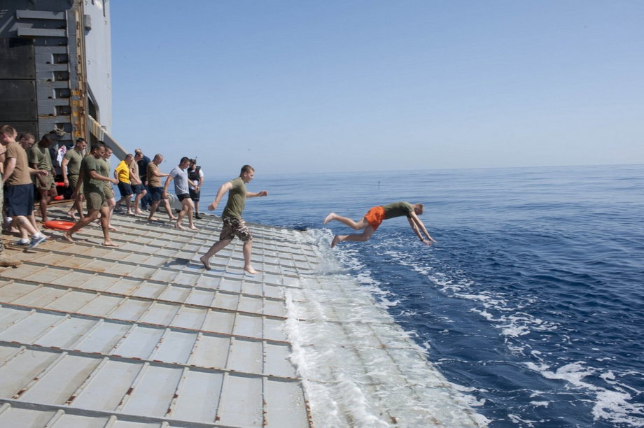 Marynarze i żołnierze piechoty morskiej na pokładzie USS Fort McHenry skaczą do Morza Śródziemnego