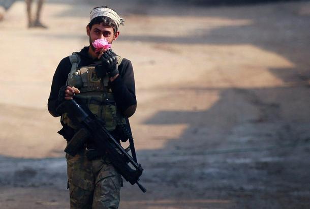 A member of the Iraqi rapid response forces holds a flower during battle with Islamic State militant