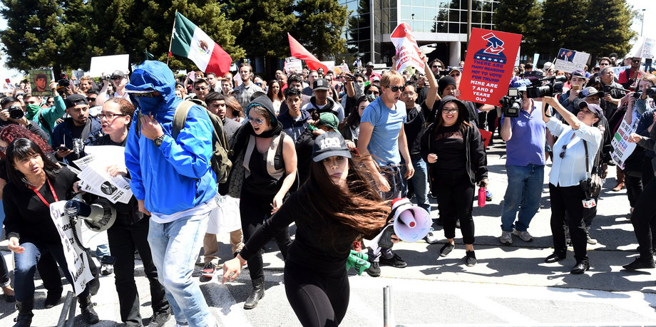 Protesters make their way over a barricade as they demonstrate against US Republican presidential candidate Donald Trump outside the Hyatt hotel, where Trump was speaking at the California GOP convention, in Burlingame, California, on April 29.