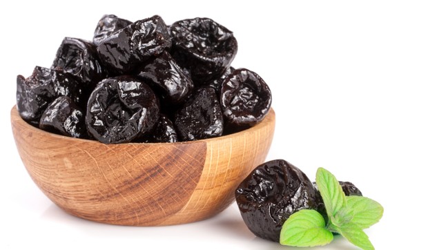 stock-photo-dried-plums-or-prunes-with-a-mint-leaf-in-wooden-bowl-isolated-on-white-background-671848381