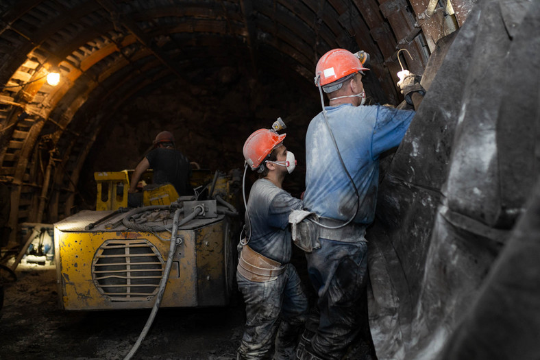 Górnicy podczas przedłużania lutniociągu doprowadzającego świeże powietrze do przodka, fot. Mateusz Paszek