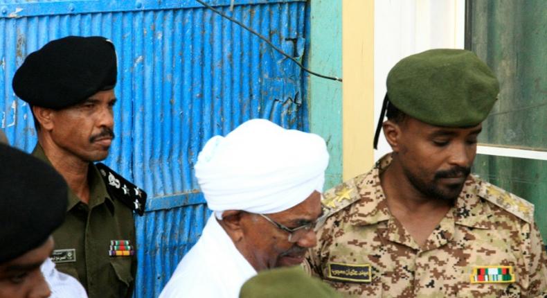 Ousted Sudanese leader Omar al-Bashir being escorted to hear charges of corruption against him in Khartoum: the Internatinal Criminal Court has called for him to face trial for genocide in Darfur