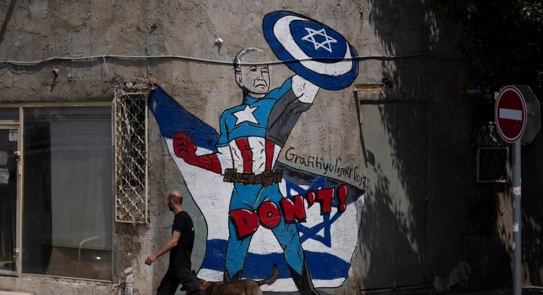 A man walks past a mural depicting US President Joe Biden as a superhero defending Israel on a street in Tel Aviv after Iran's missile and drone attacks that began Saturday.Leo Correa/AP Photo