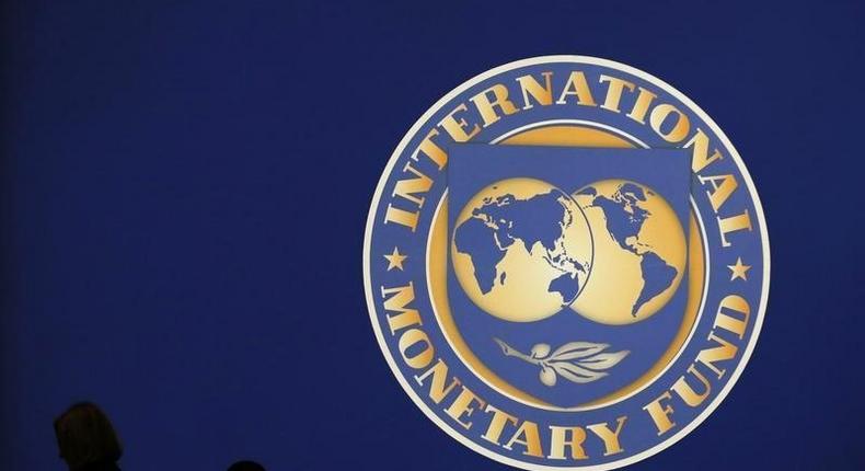 Visitors are silhouetted against the logo of the International Monetary Fund at the main venue for the IMF and World Bank annual meeting in Tokyo October 10, 2012. 