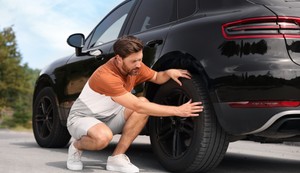 Muškarac proverava gume na vozilu