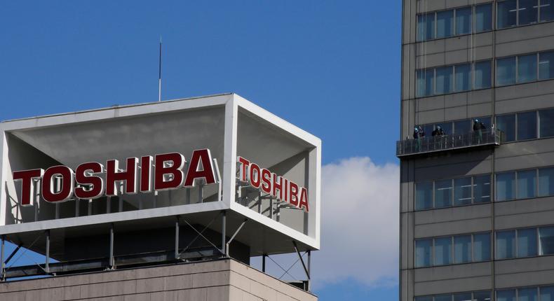 The logo of Toshiba Corp is seen as Window cleaners work on the company's headquarters in Tokyo
