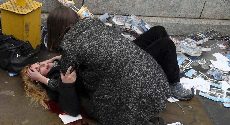 A woman helps a victim of the terror attack which a car plough down pedestrians on London Bridge on Saturday, June 3, 2017.