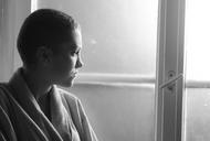 Young depressed cancer patient standing in front of hospital window
