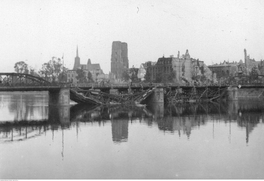 Wrocław, panorama Ostrowa Tumskiego. Na pierwszym planie Odra i uszkodzony most Lessinga (widoczne dwa zniszczone przęsła). W głębi zabudowa Ostrowa Tumskiego, m.in. archikatedra św. Jana Chrzciciela, kościół św. Krzyża i św. Bartłomieja (z lewej). Widoczne zniszczenia wojenne.