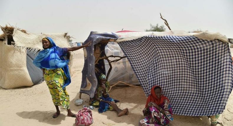 This photo taken on June 19, 2016 in the village of Kidjendi near Diffa shows women standing near makeshift tent in a camp as displaced families fled from Boko Haram attacks in Bosso
