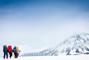 Group with gear and backpacks crossing icy field to mountain