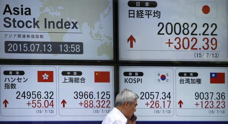 A man walks past in front of an electronic board displaying various Asian countries' stock price index outside a brokerage in Tokyo July 13, 2015.   REUTERS/Issei Kato