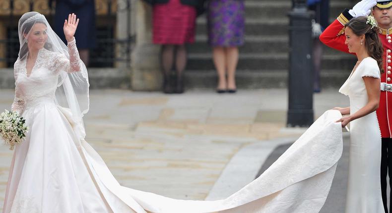 Catherine Middleton waves to the crowds as her sister and Maid of Honour Pippa Middleton holds her dress before walking in to the Abbey to attend the Royal Wedding of Prince William to Catherine Middleton at Westminster Abbey on April 29, 2011 in London, England.