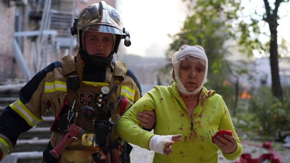 Ratownik pomagający poszkodowanej osobie w miejscu ostrzału w Kijowie, 10.10.2022 r.